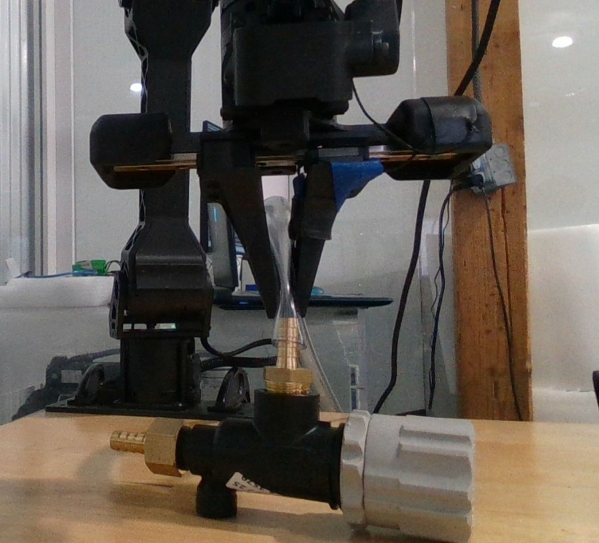 Robot gripper inserting a clear tube onto a brass fitting on the Tensiq test bench